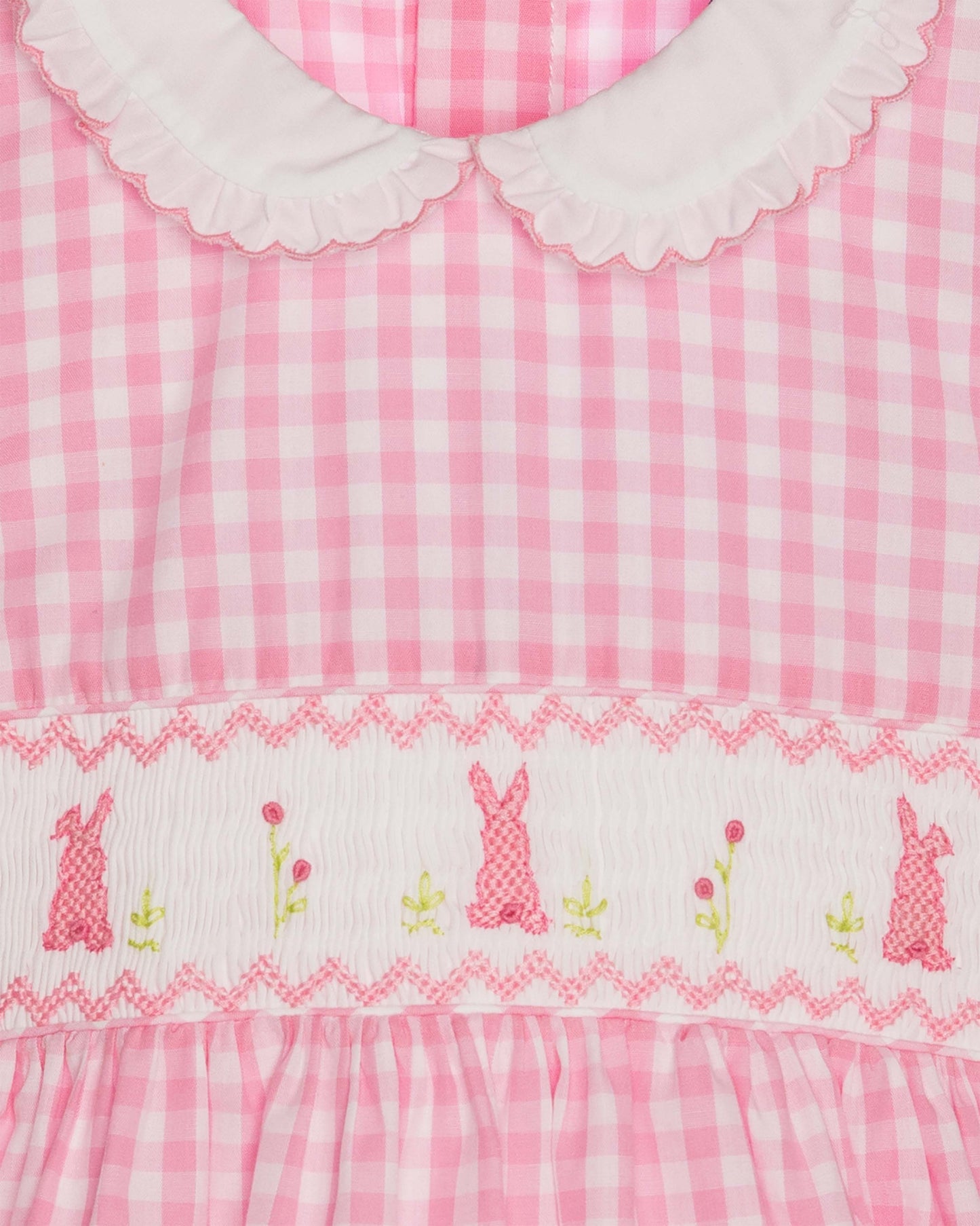 Pink gingham dress with embroidered bunnies and flowers on a white background