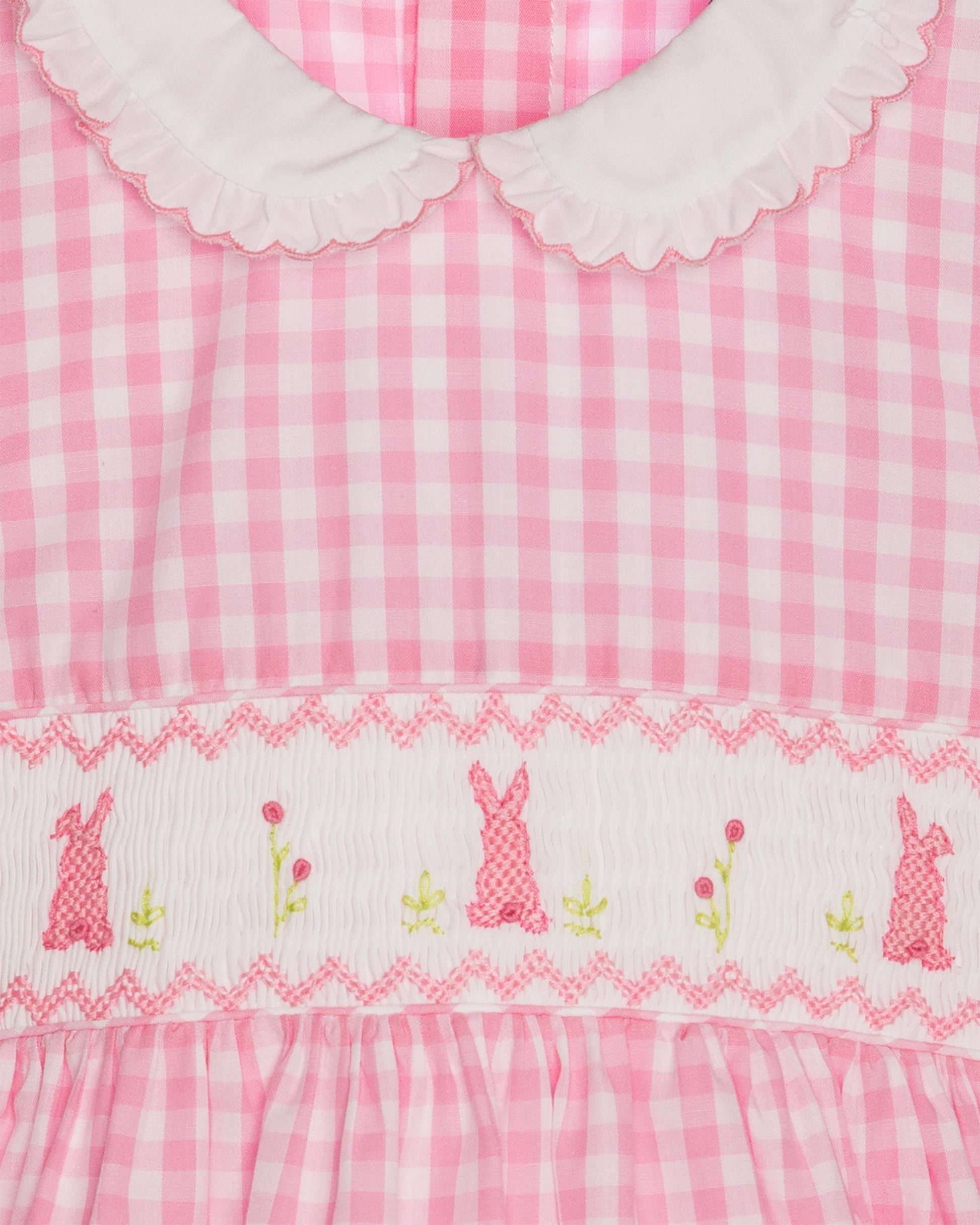 Pink gingham dress with embroidered bunnies and flowers on a white background