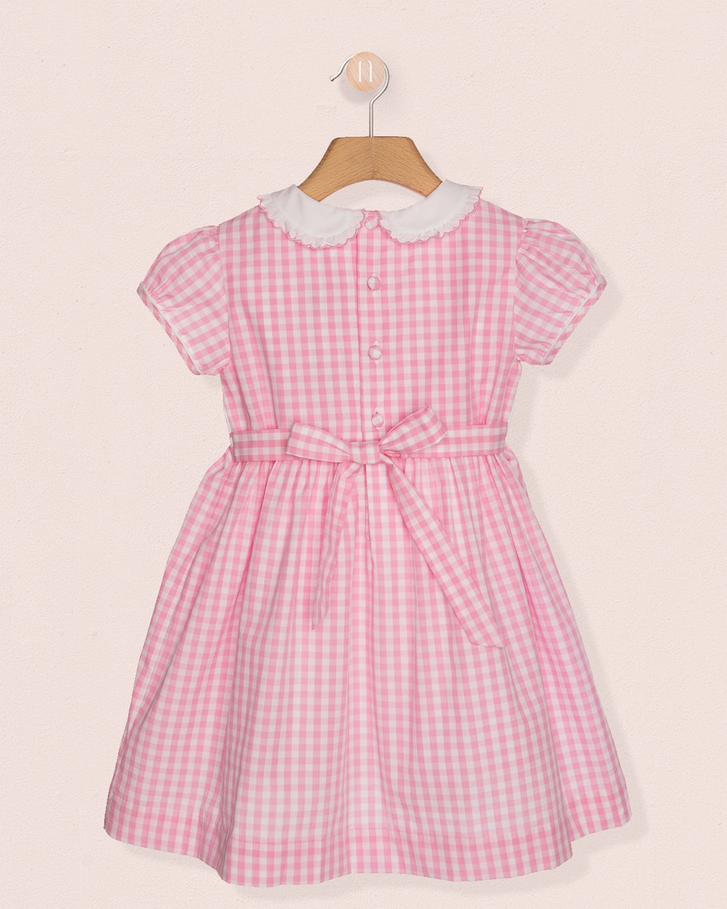 Back of Pink checkered dress with white collar on a beige background