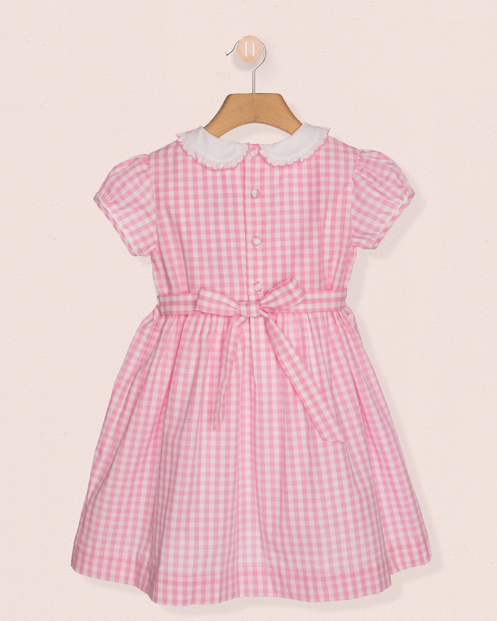 Back of Pink checkered dress with white collar on a beige background