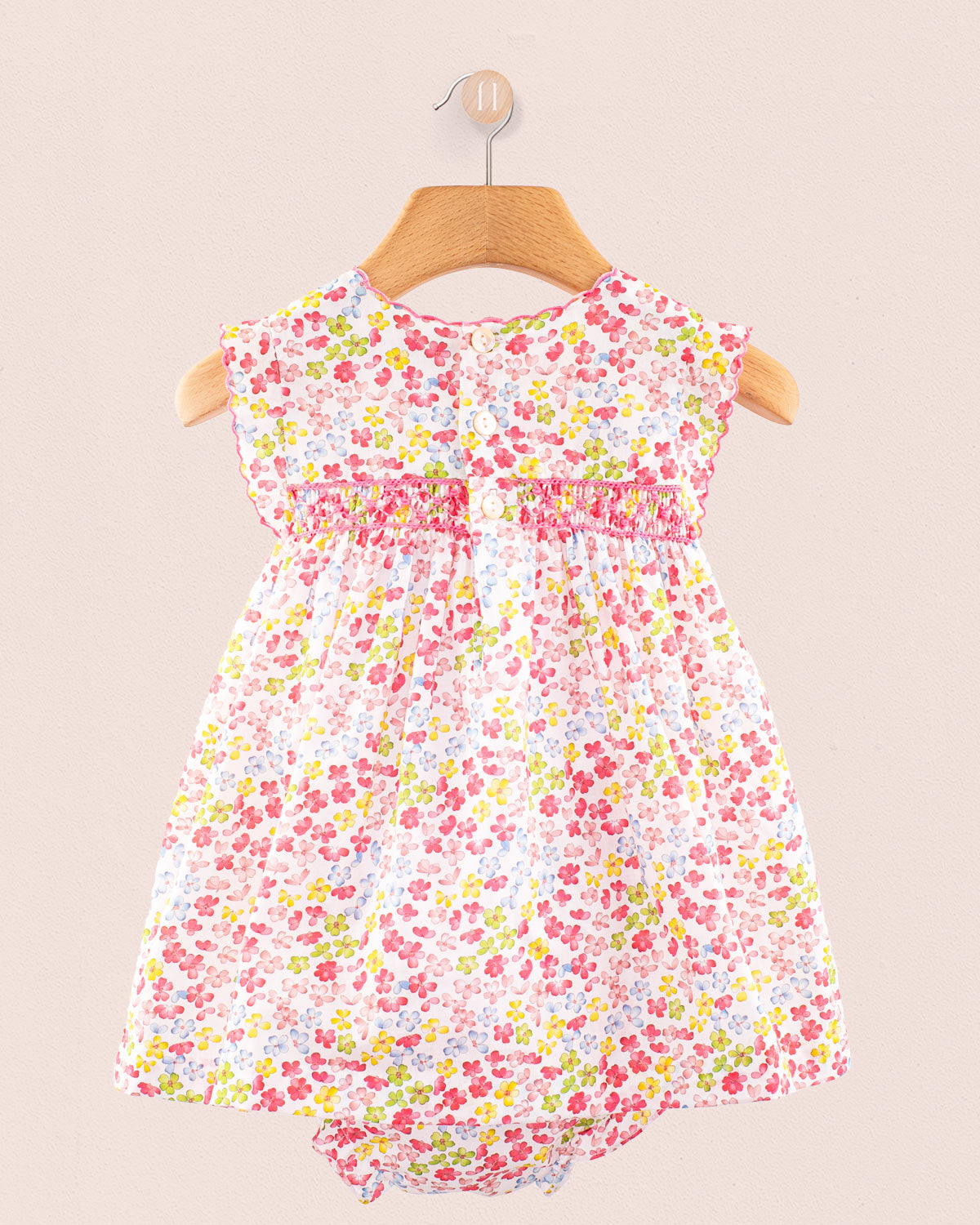 Back view of Baby Amelie floral dress showing gathered waist detail and fabric flow on hanger