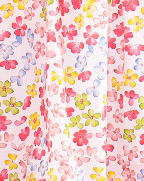 Close-up of Baby Amelie dress showing detailed floral print in pink yellow red and blue on white cotton fabric