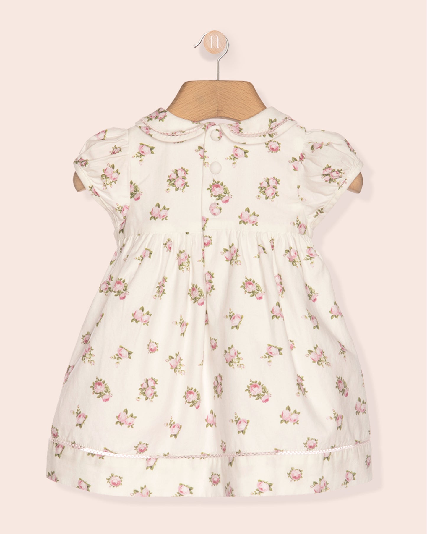 Floral dress on a mannequin against a light pink background