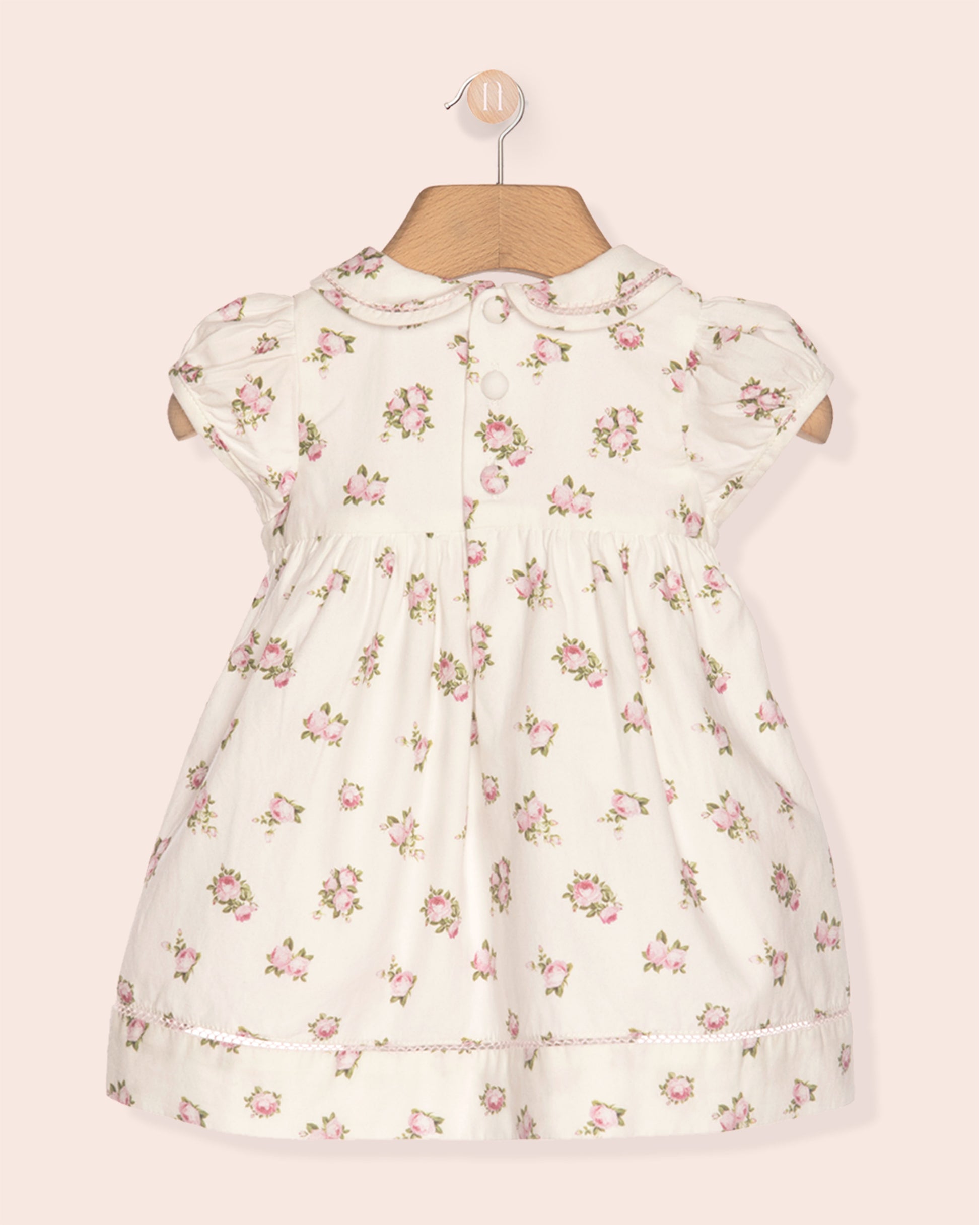Floral dress on a mannequin against a light pink background