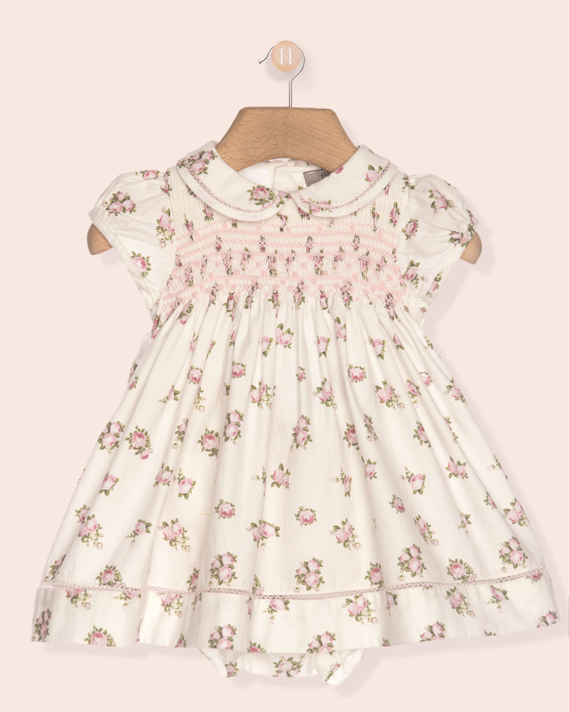 Floral dress on a hanger against a light pink background