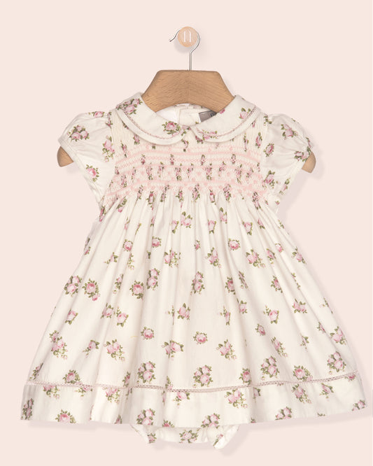 Floral dress on a hanger against a light pink background