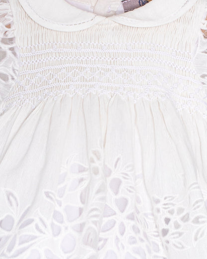 Close-up of the Baby Emmy Doppia White Smock Dress bodice, highlighting the hand-smocked panel and floral laser-cut embroidery.