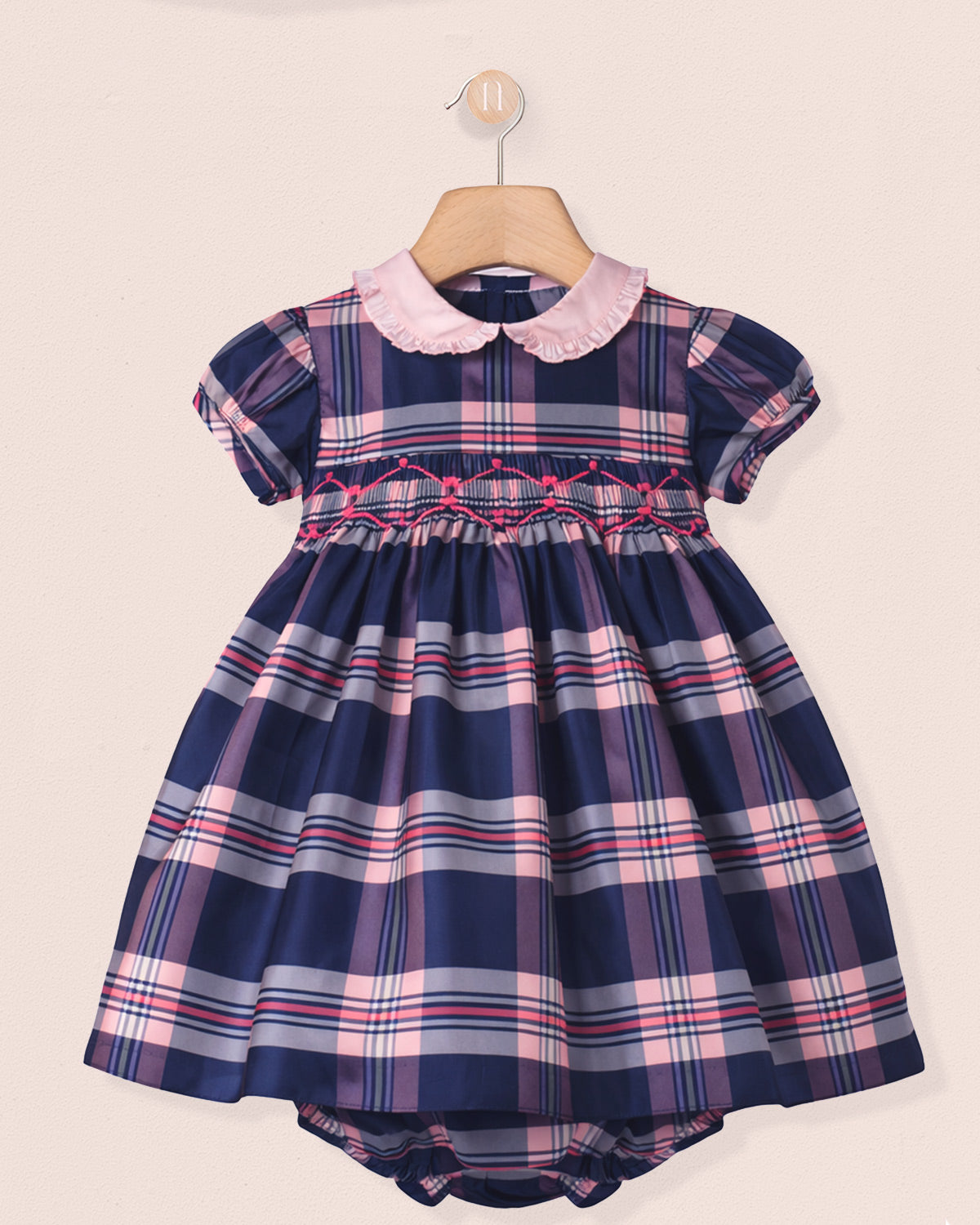 Navy and pink plaid dress with a pink collar on a beige background
