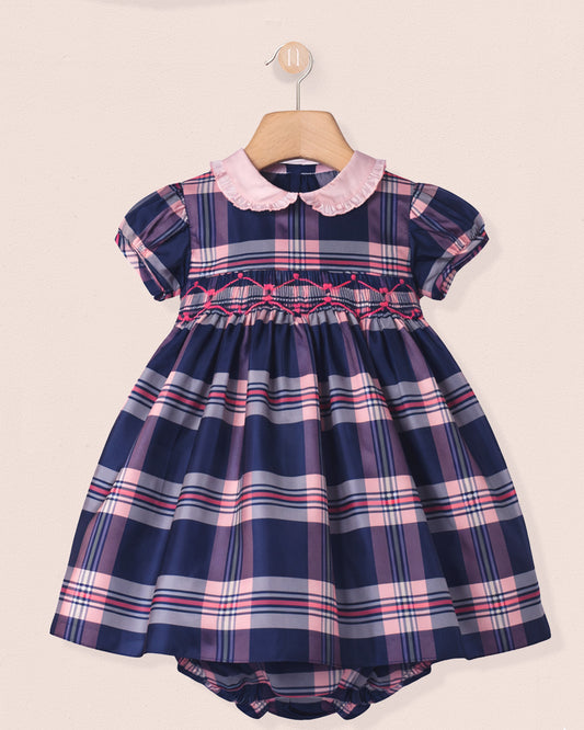 Navy and pink plaid dress with a pink collar on a beige background