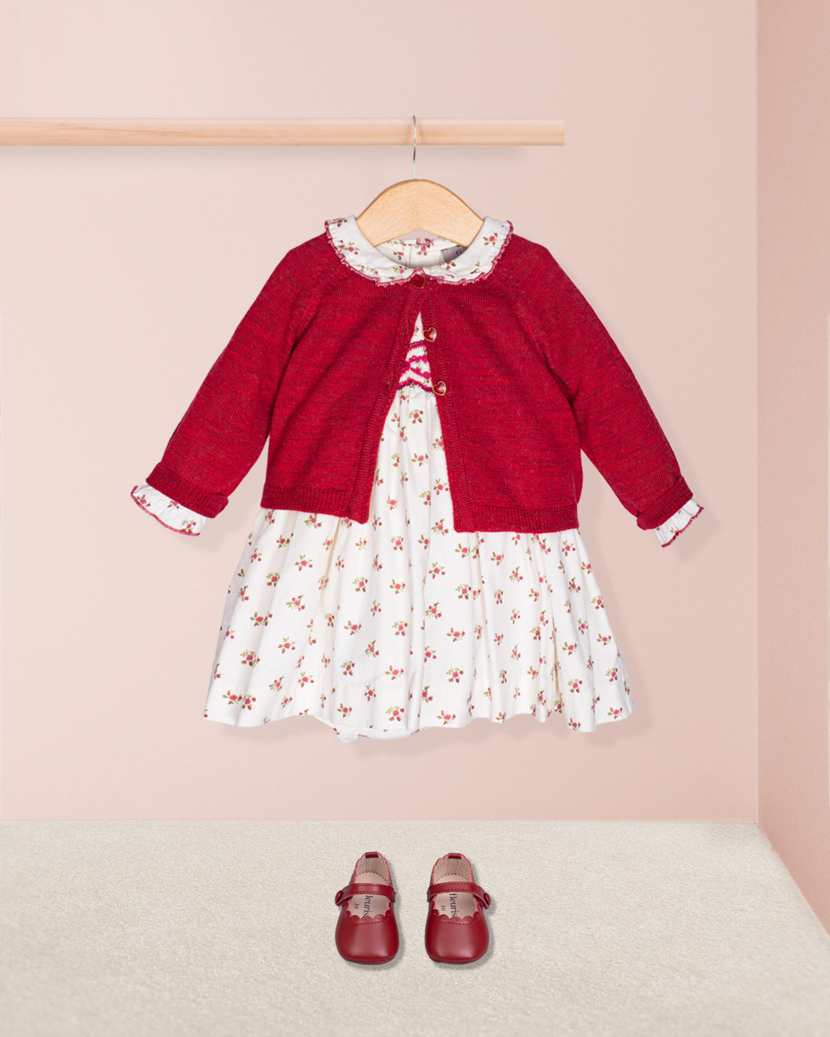 Red sweater over a white dress with floral pattern, paired with red shoes on a pink background