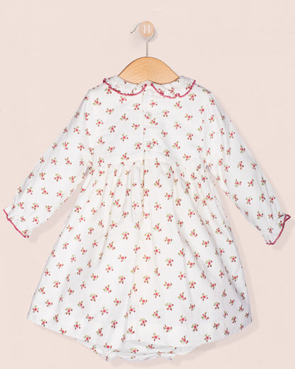 White dress with red floral pattern on a beige background