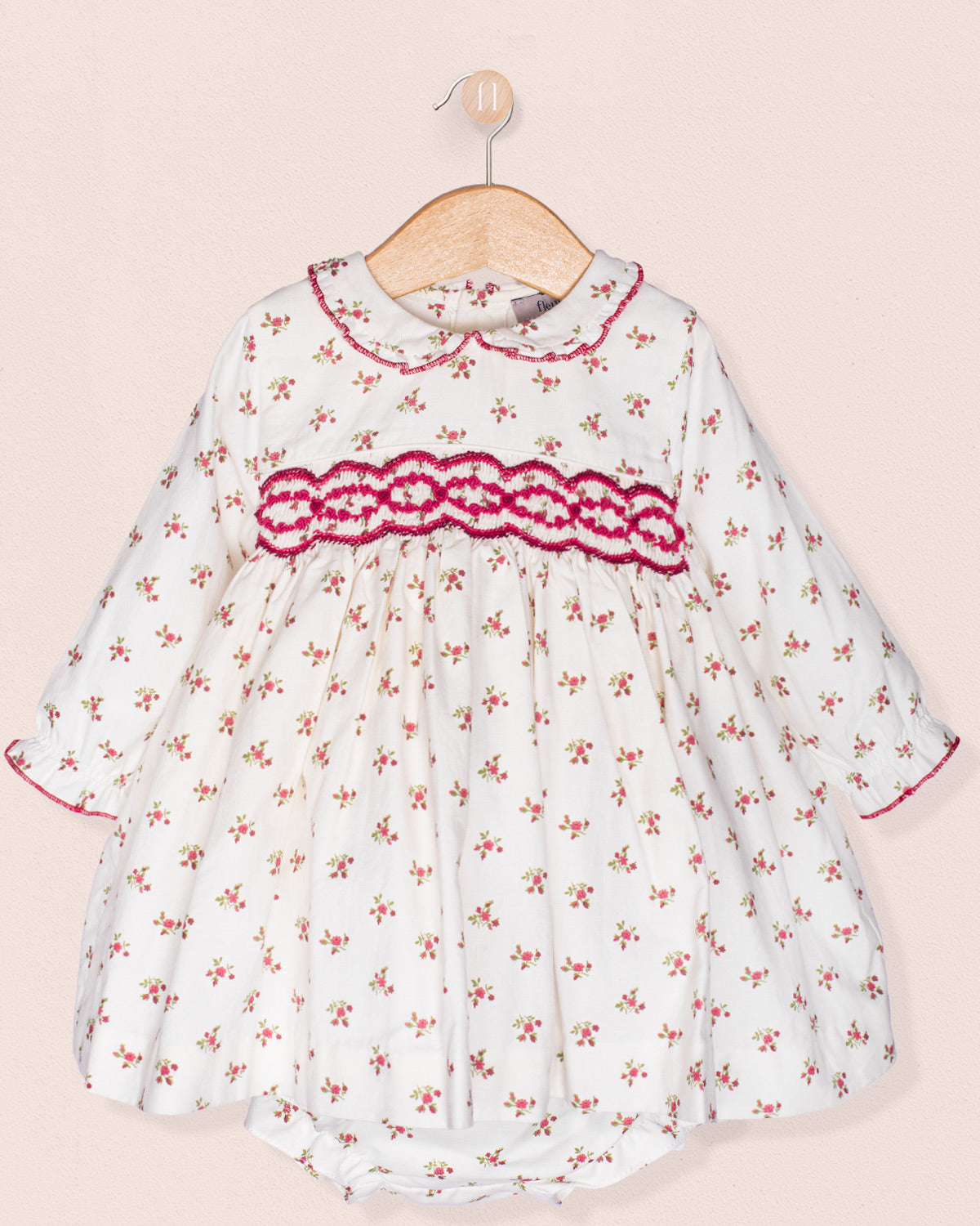 White dress with red floral pattern and trim on a beige background