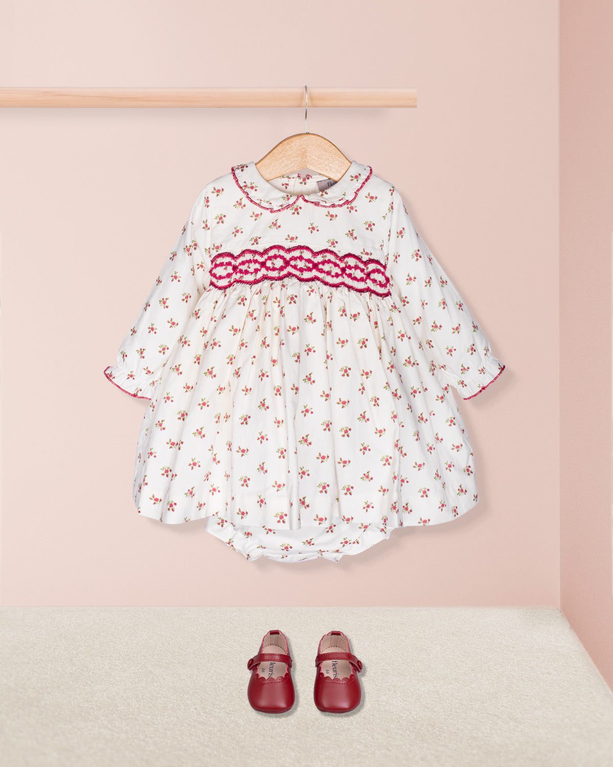 White dress with red floral pattern and matching shoes on a pink background