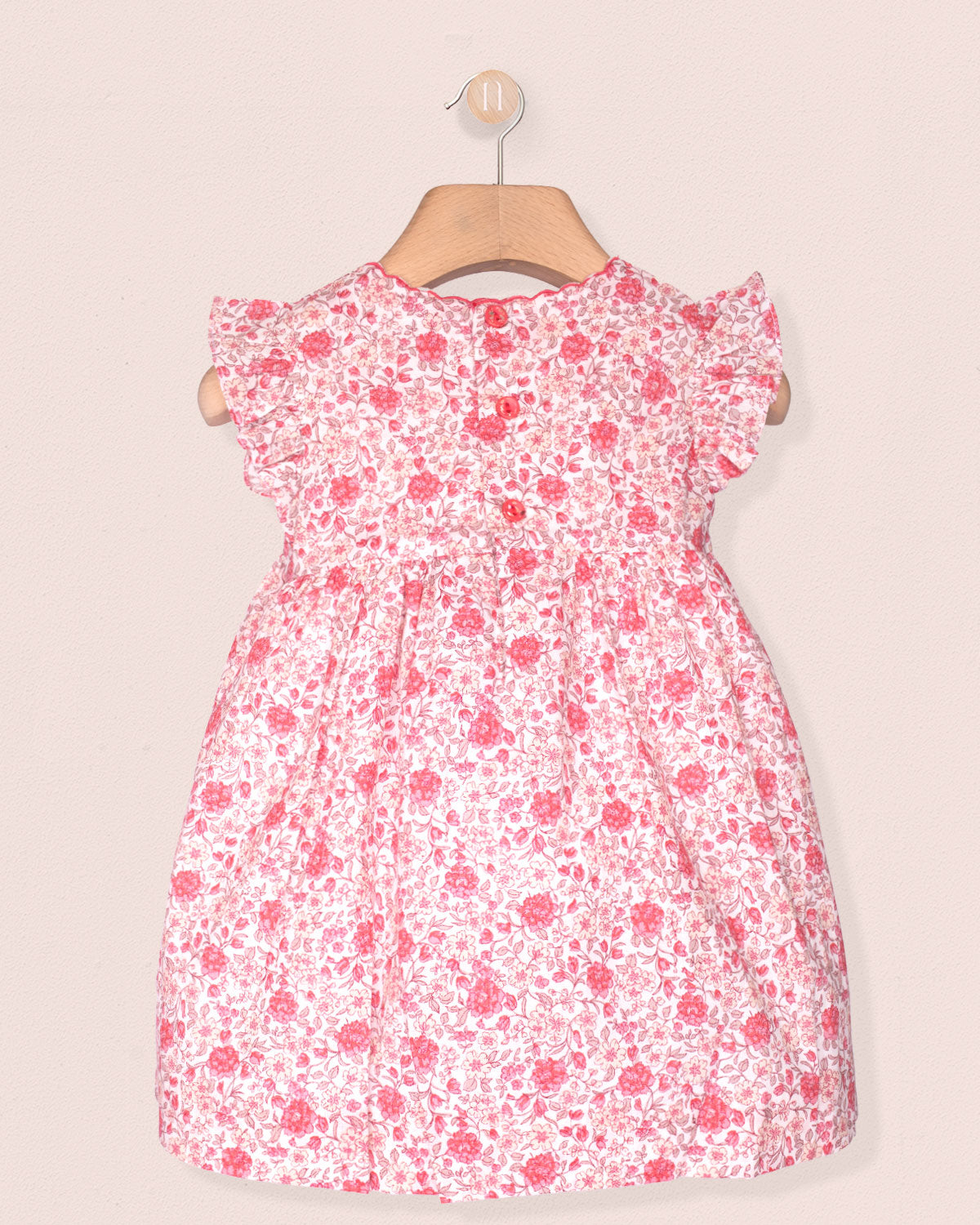 back of pink Floral dress on a hanger against a plain background
