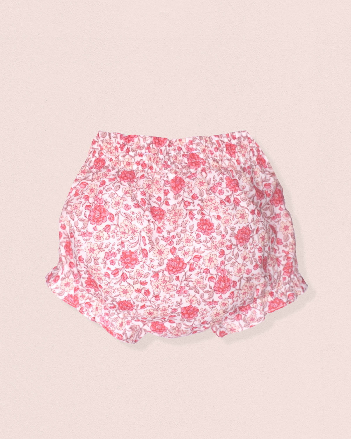 Floral-patterned baby bloomers on a beige background