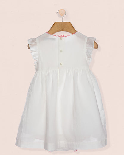 White dress on a hanger against a light pink background