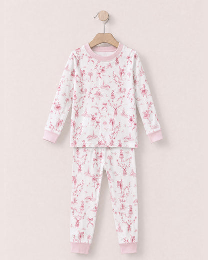 white pajamas with reddish pink toille, bows and ballerinas design, with pink collars and cuffs, on a hanger against a peach neutral background.