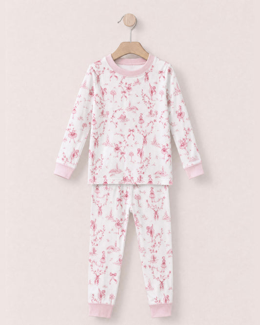 white pajamas with reddish pink toille, bows and ballerinas design, with pink collars and cuffs, on a hanger against a peach neutral background.