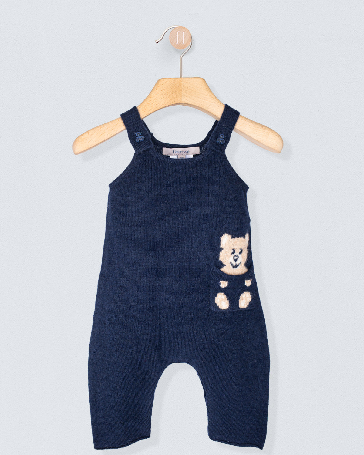 Navy blue baby romper with teddy bear design on a hanger against a light gray background