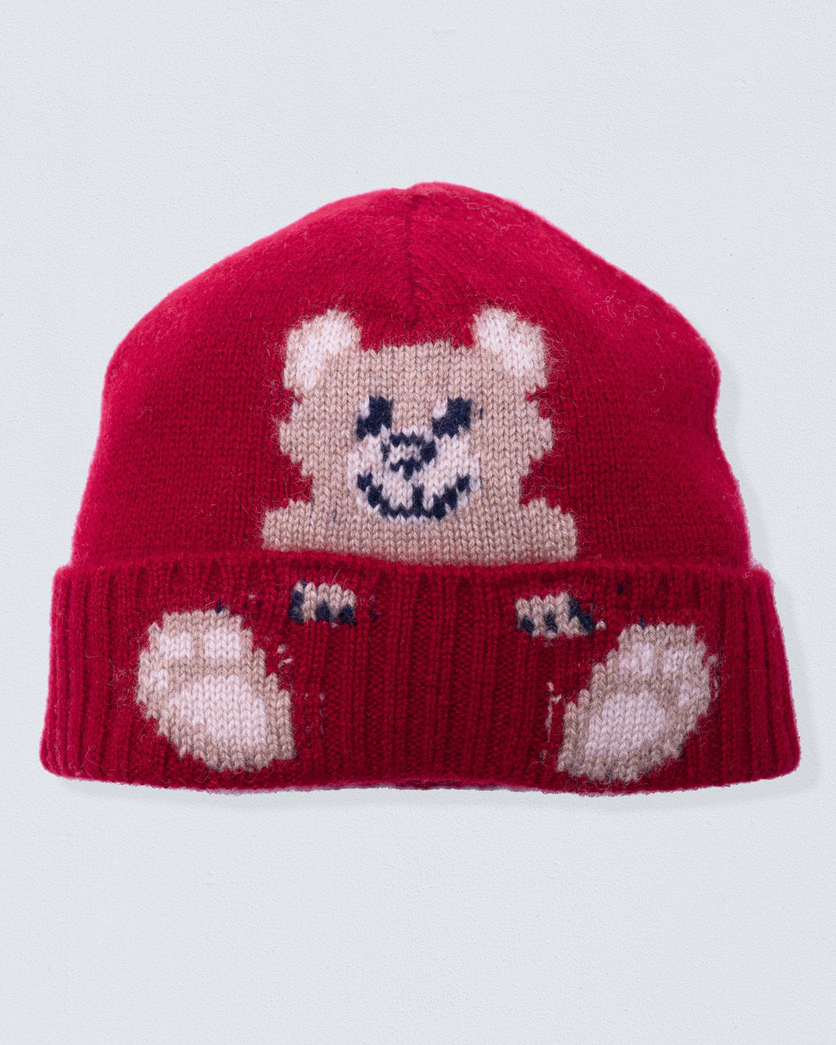 Red knit beanie with a bear face design on a light gray background
