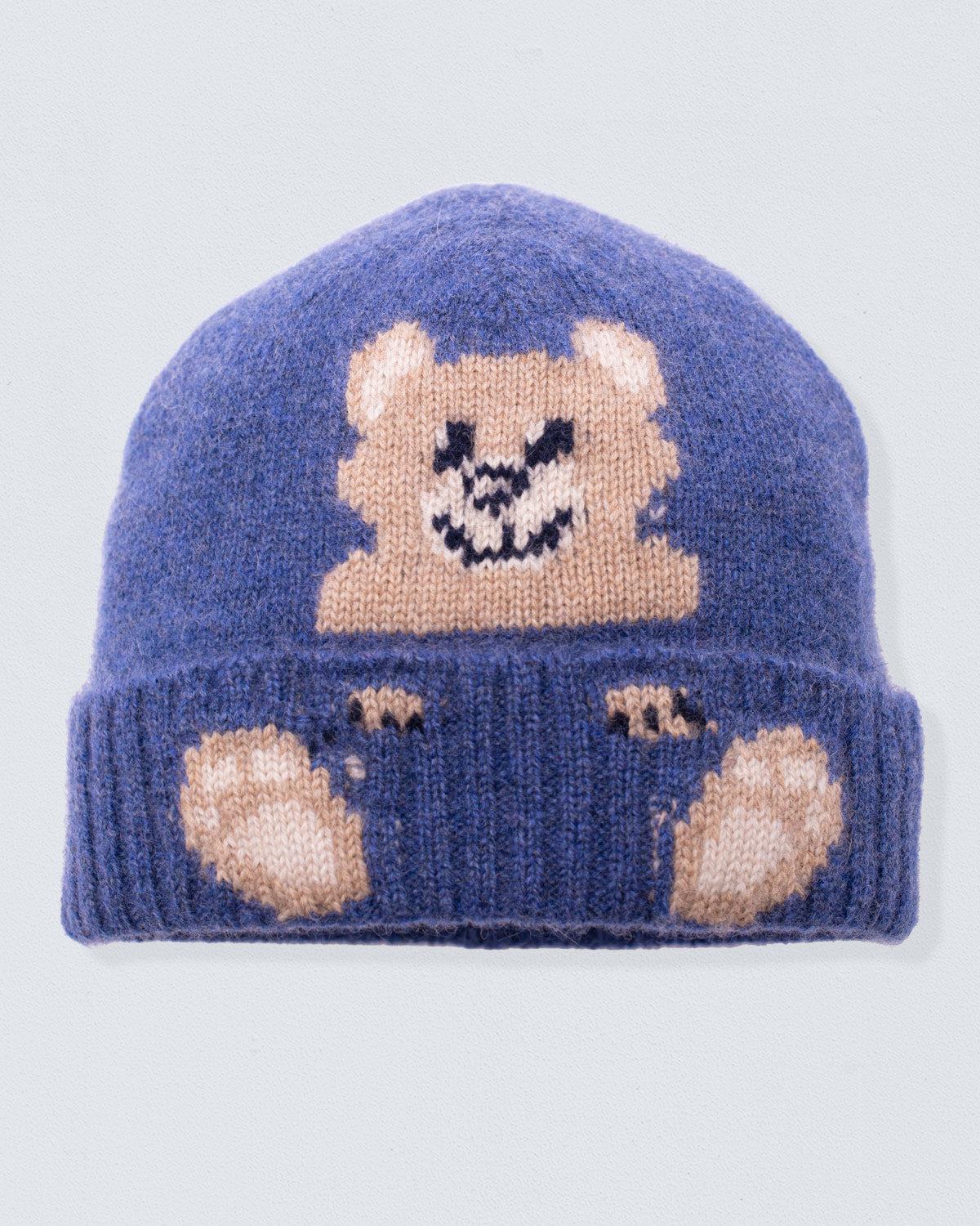 Blue knit beanie with bear design on a light gray background