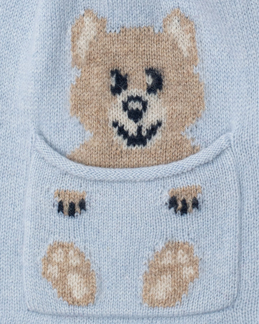 Close-up of pocket on Light blue knitted fabric with a bear face and paw prints design.
