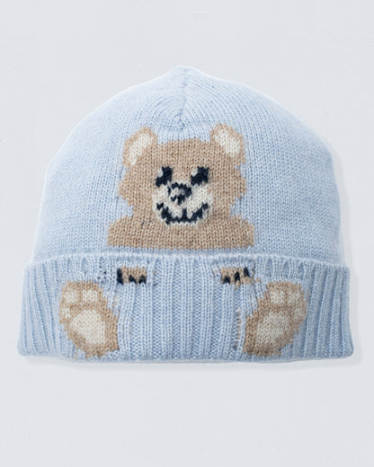 Light blue knit baby hat with teddy bear design on a light gray background
