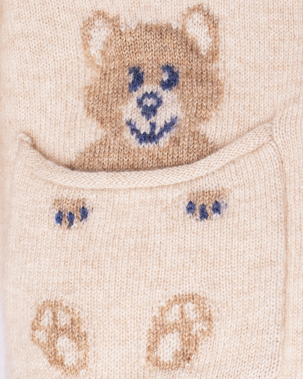Close-up of a knitted baby bootie with a bear design on a beige background