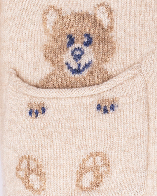 Close-up of a knitted baby bootie with a bear design on a beige background