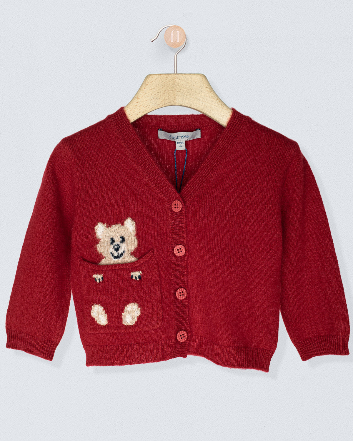 Red children's cardigan with bear design on a hanger against a light gray background