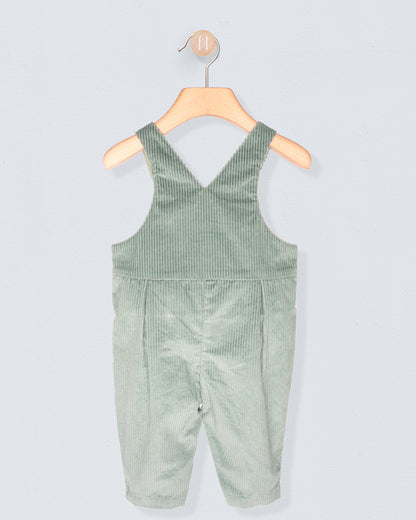 Back of Green corduroy overalls on a wooden hanger against a light gray background