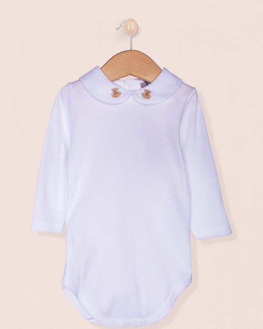 White long-sleeve Italian cotton baby onesie with a beige scalloped-round collar featuring two hand-embroidered beige teddy bears, hanging on a wooden hanger against a soft blush background.