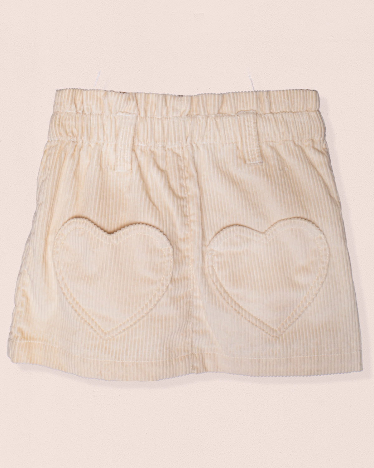 Beige skirt with heart cutouts on a light pink background