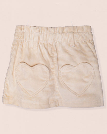 Beige skirt with heart cutouts on a light pink background