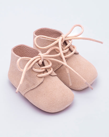 Beige baby shoes with laces on a light gray background