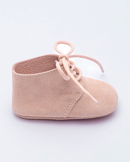 Beige baby shoe with soft sole on a light purple background