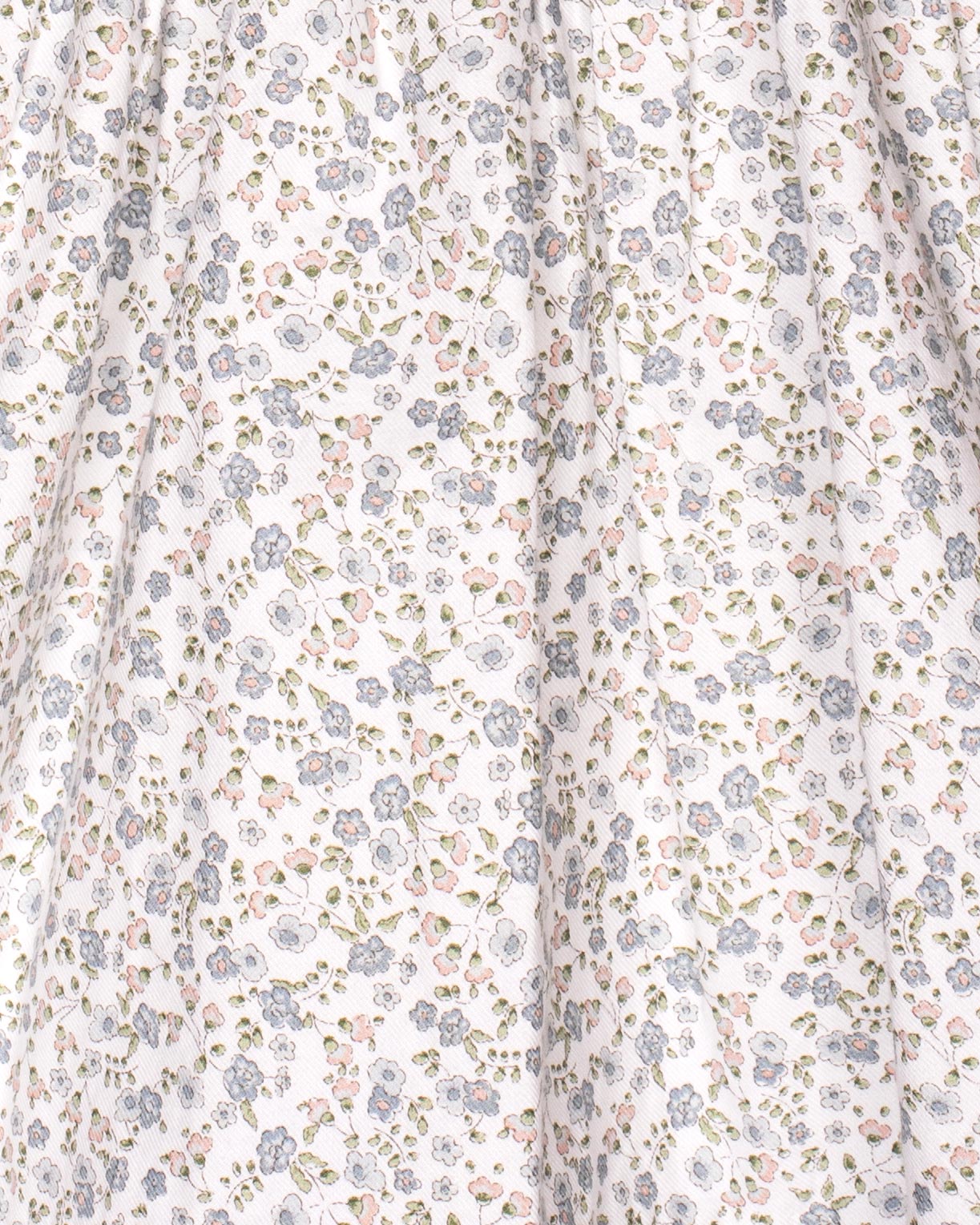 A close-up of the dress’s floral twill fabric, highlighting the fine print of blue, pink, and green flowers scattered across the white background.