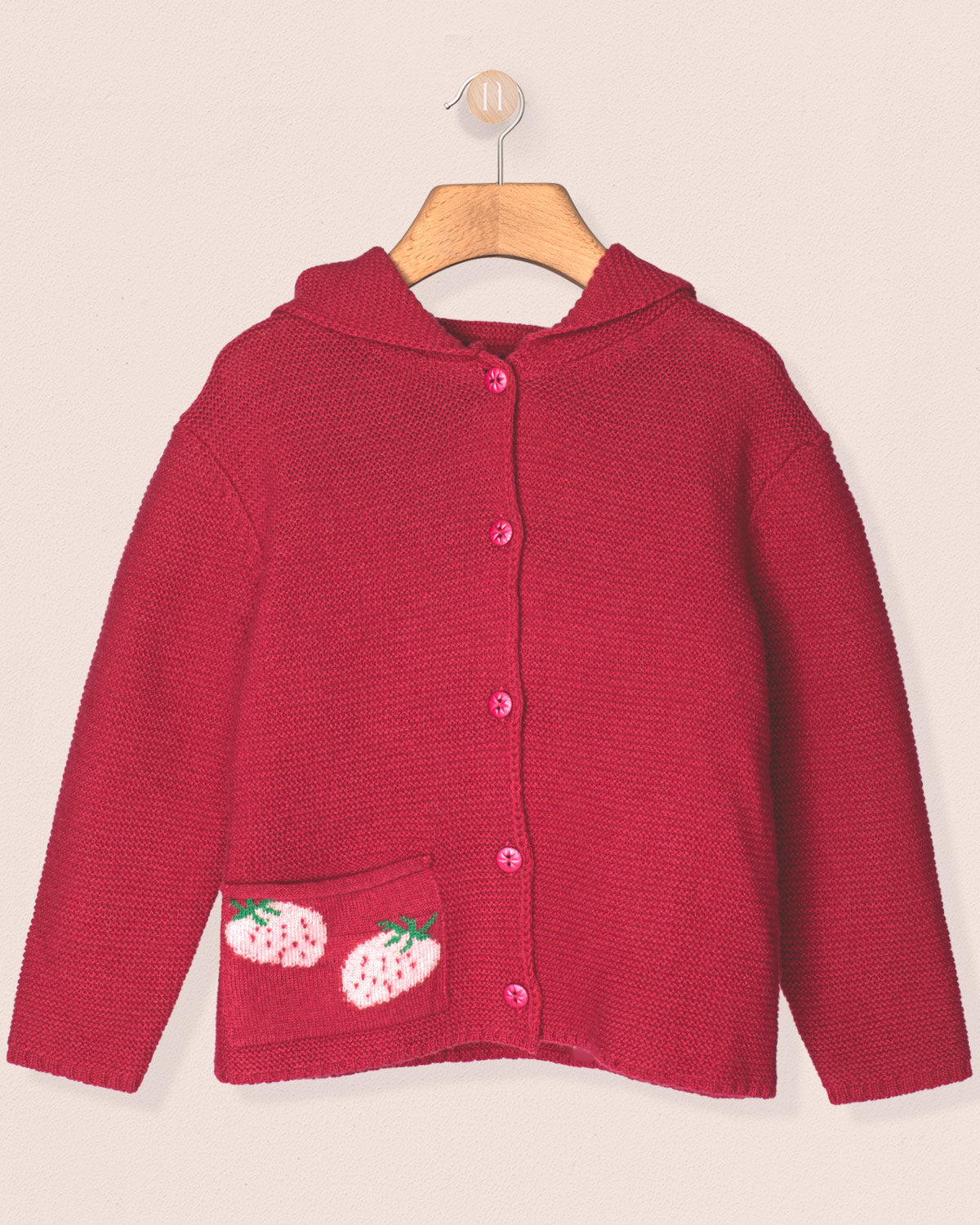 Fuchia children's cardigan with strawberry designs on a beige background