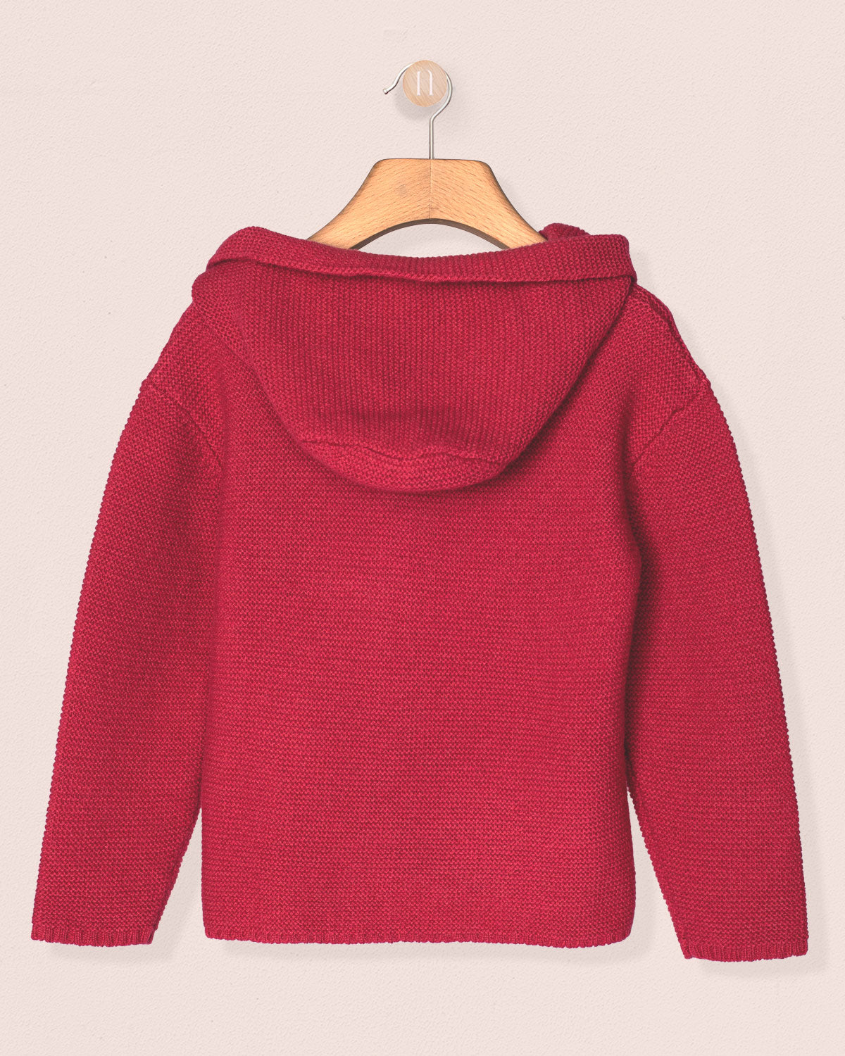 fuchia knitted sweater on a hanger against a light pink background
