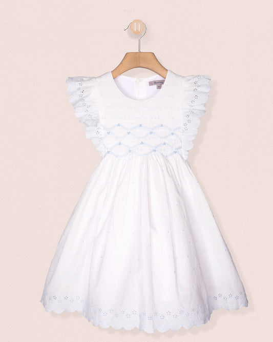 White dress with blue floral embellishments on a beige background