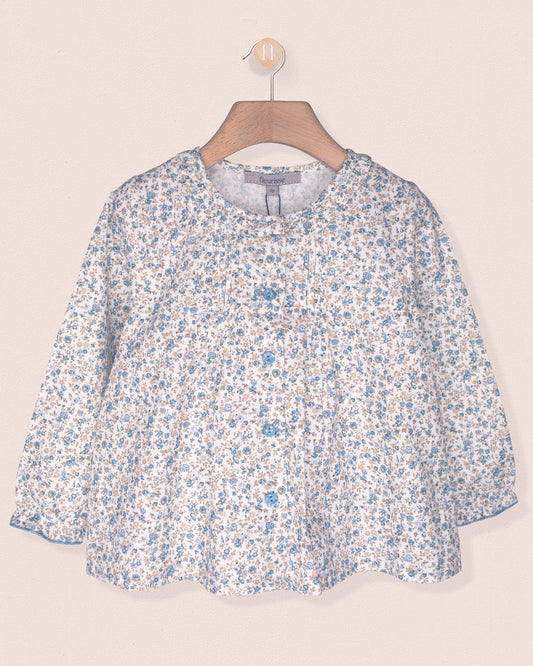 Floral patterned blouse on a hanger against a beige background