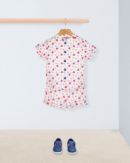 Short sleeve white shirt with red and blue boats with matching shorts, on a hanger with blue shoes on the floor below