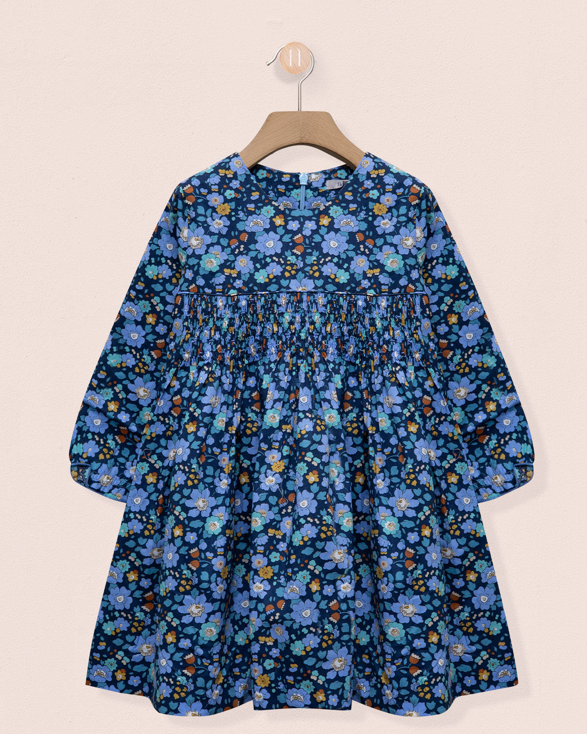 Blue floral dress on a hanger against a beige background