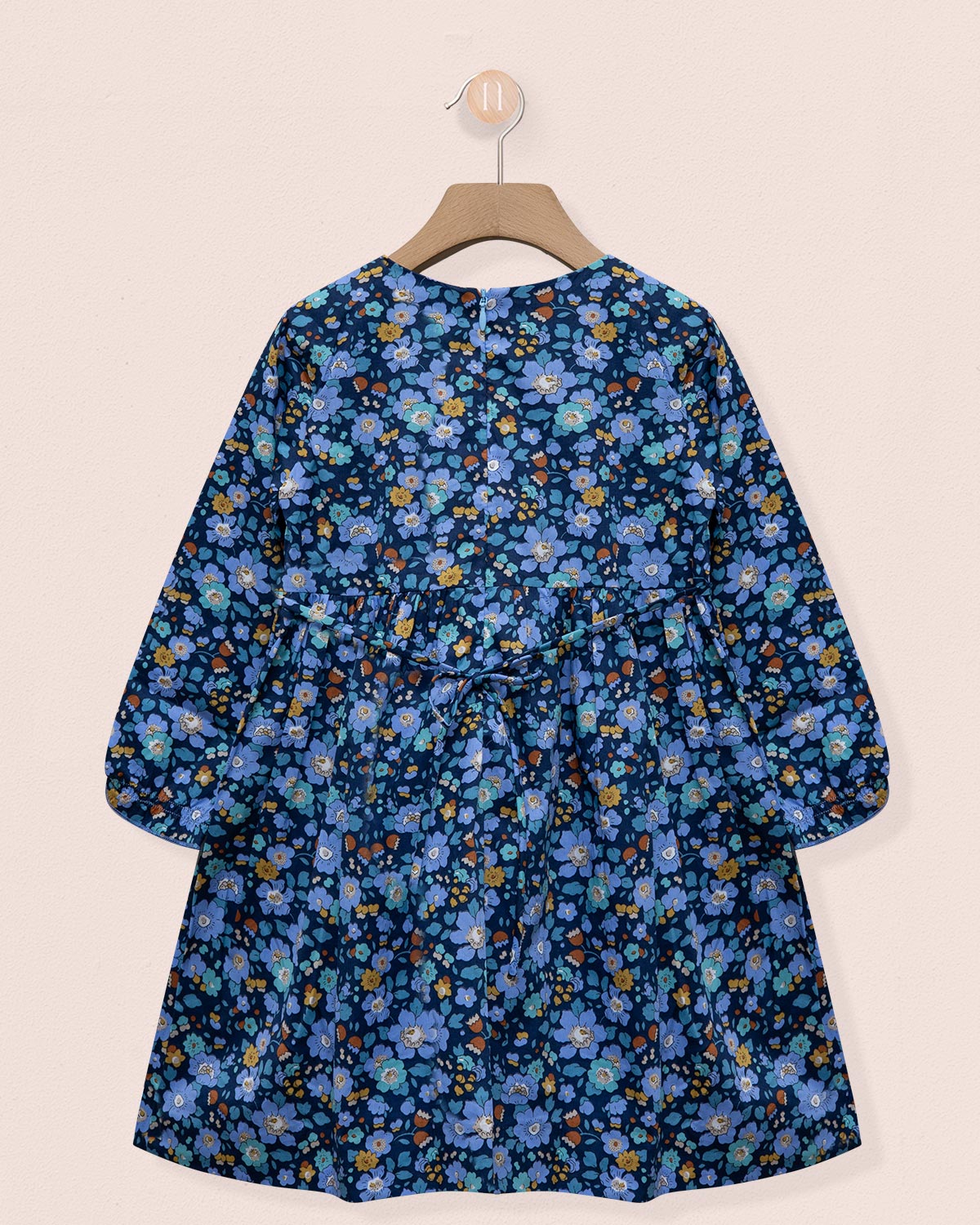 Blue floral dress on a hanger against a beige background