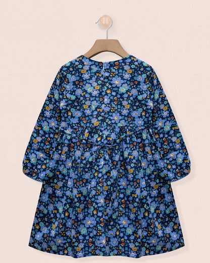 Blue floral dress on a hanger against a beige background