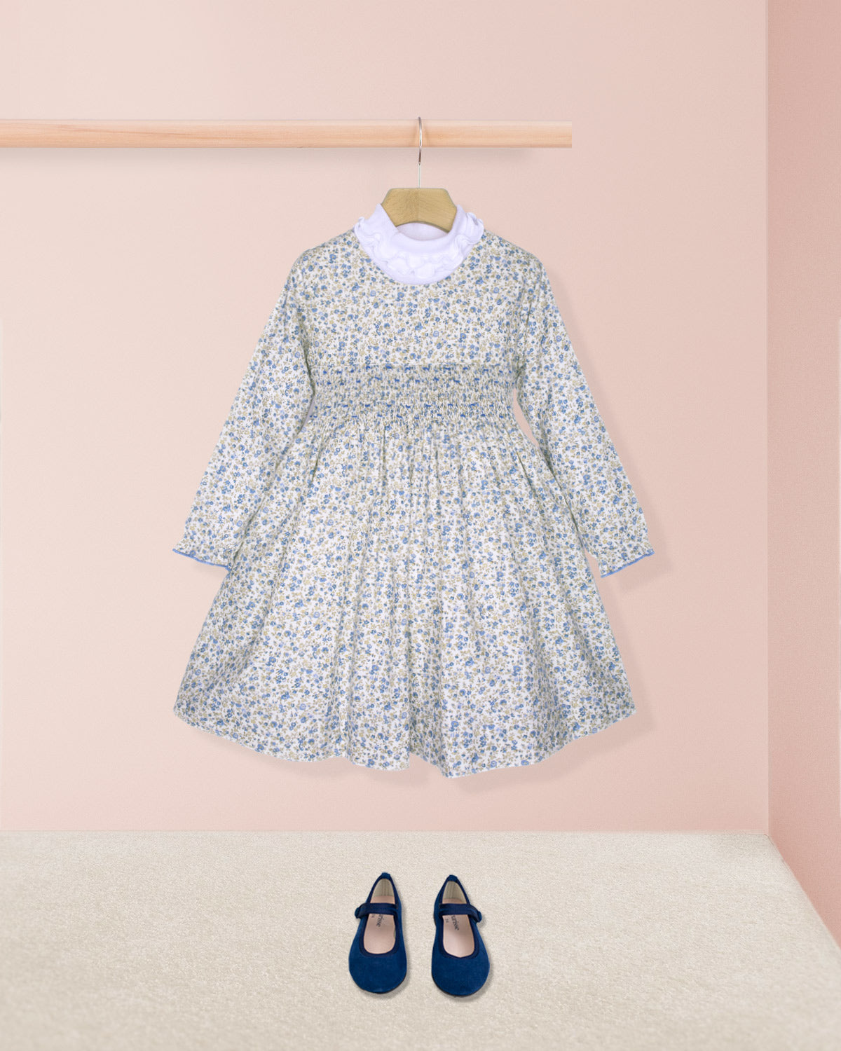 Floral dress with long sleeves and a white collar, paired with navy blue shoes on a pink background.