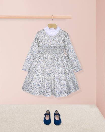 Floral dress with long sleeves and a white collar, paired with navy blue shoes on a pink background.
