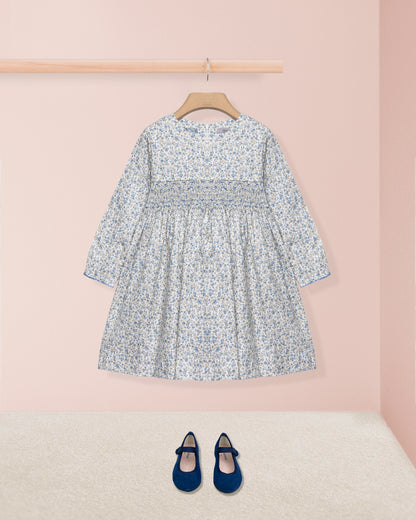 Floral dress on a hanger with matching shoes on a pink background