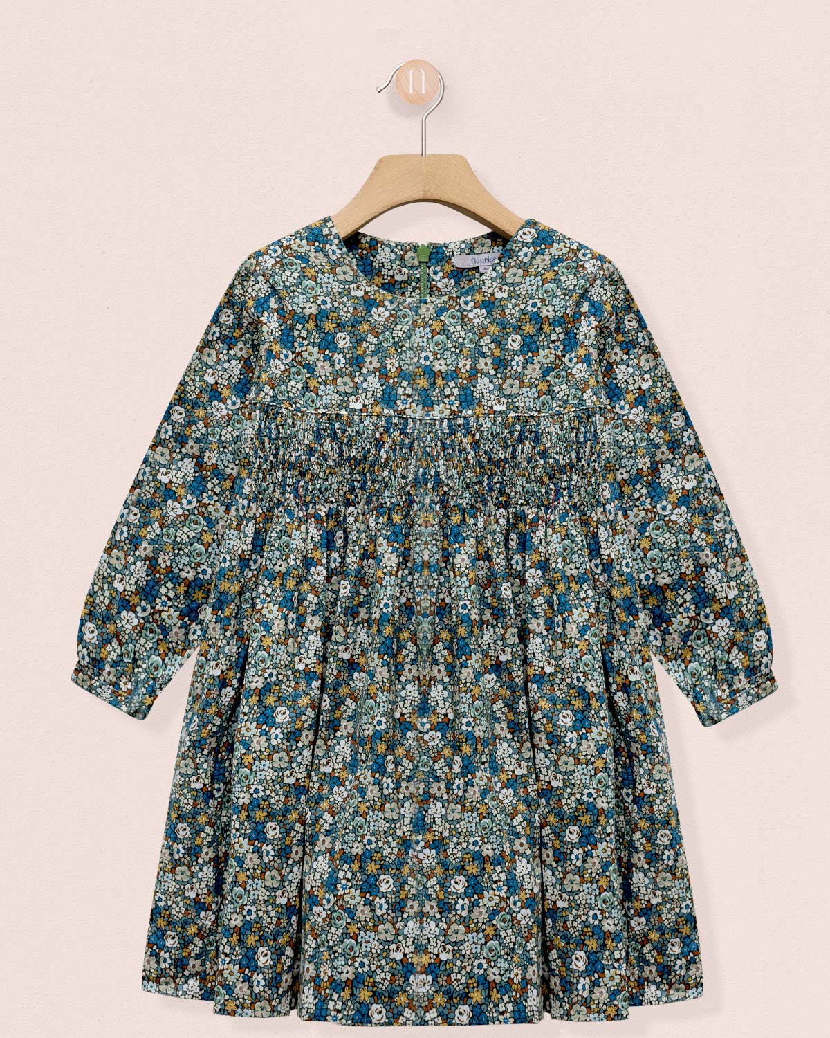 Floral dress on a hanger against a light pink background