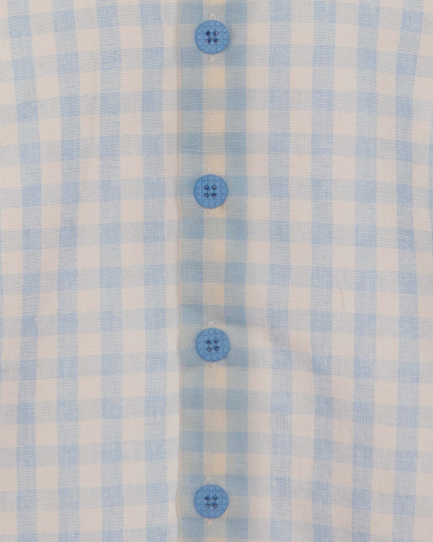 Closeup of light blue and white checkered shirt and blue buttons.